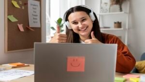 Jovem animado com fones de ouvido, celebrando frente ao notebook com um post-it sorridente