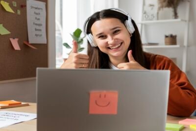 Jovem animado com fones de ouvido, celebrando frente ao notebook com um post-it sorridente